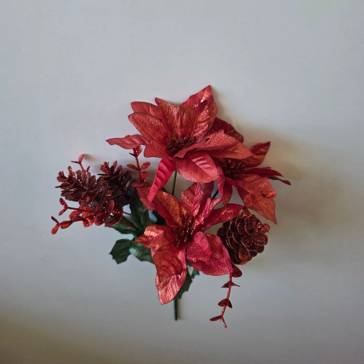 Red shimmer Christmas poinsettia flower bunch with pine cones